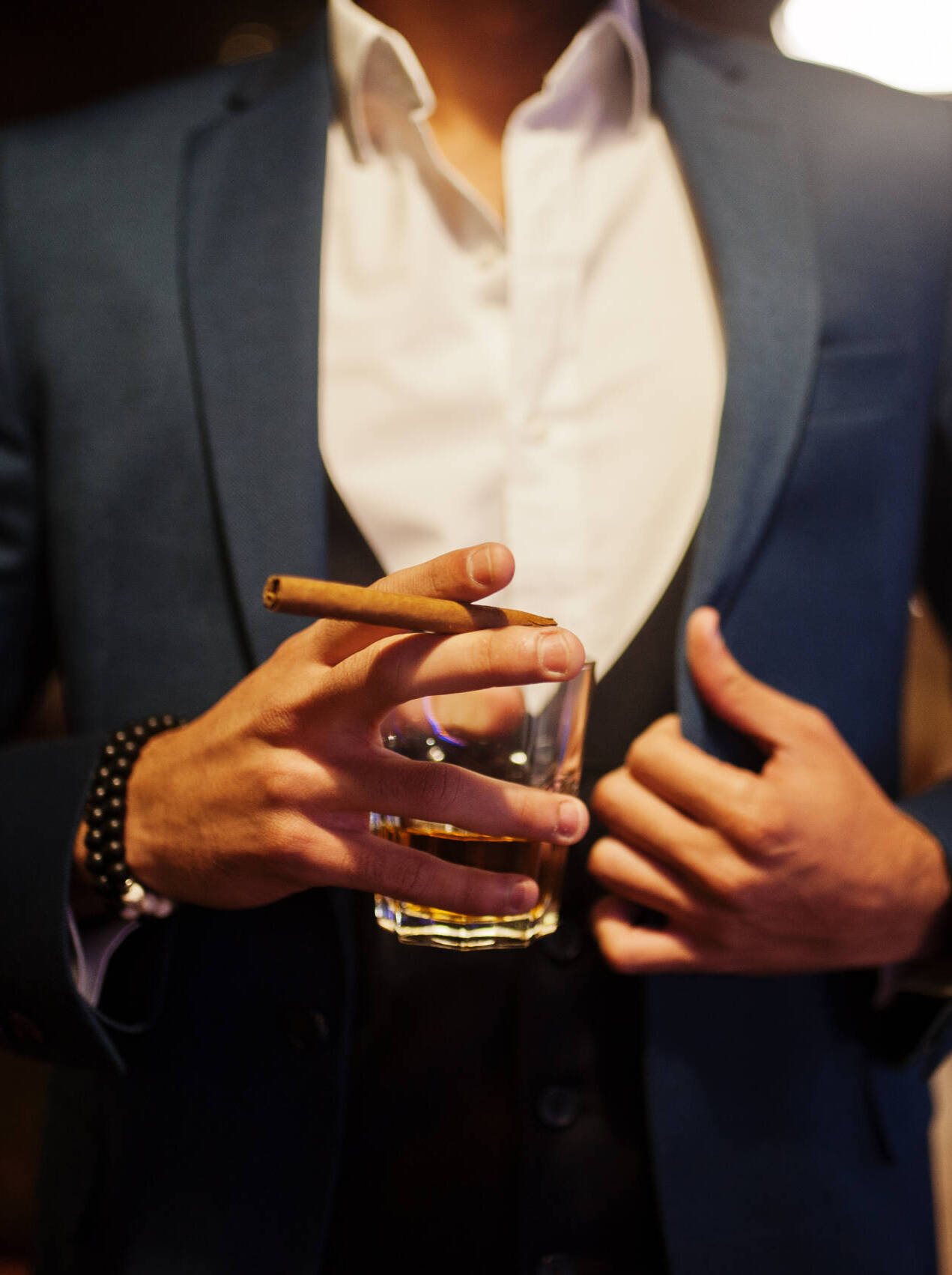 Close up hand of handsome well-dressed arabian man with glass of Close up hand of handsome well-dressed arabian man with glass of whiskey and cigar posed at pub.