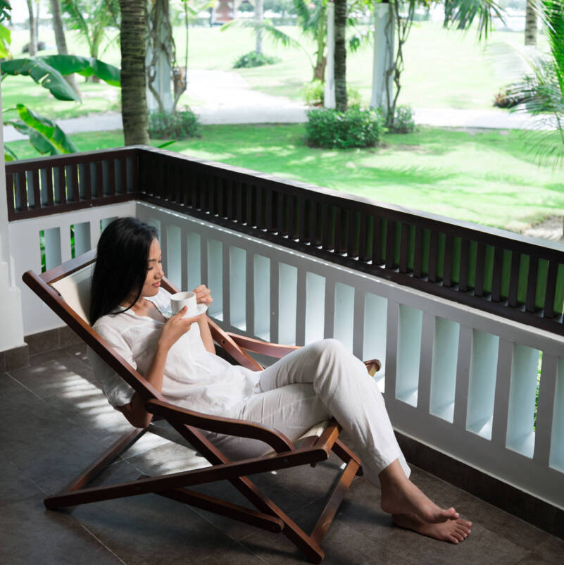 Resort place Vertical image of a serene young lady resting in the sunbed in the tranquil resort place